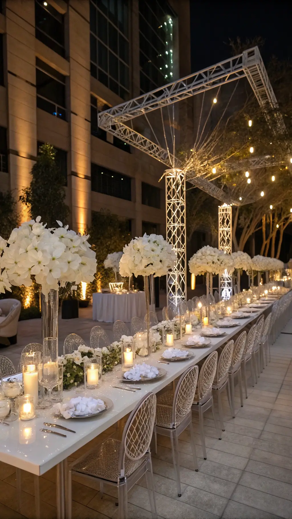 Creating White Christmas Wedding Centerpieces Intimate winter reception with ghost chairs around lucite tables adorned with cascading white orchids, baby's breath, and warm candlelit reflections.
