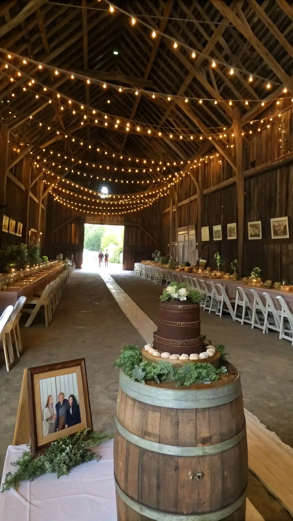 50th Wedding Anniversary Chocolate Cake Ideas A warmly lit historic barn interior with cafe lights, showcasing a rustic chocolate peanut butter cake on a wine barrel, surrounded by wooden chairs and harvest tables with flowing runners and potted herbs; vintage couple photographs in antique frames enhance the cozy, nostalgic ambiance. 50th Wedding Anniversary Chocolate Cake