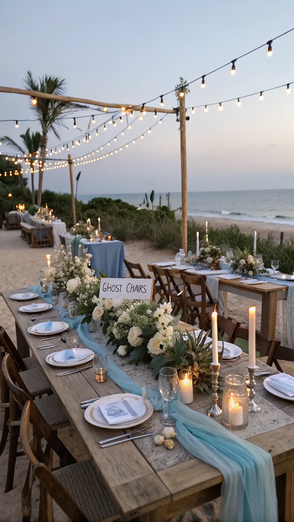 How to Plan a Dream Beach Wedding Reception Oceanfront dining setup with farm tables, blue runners, brass candlesticks, orchids, sea glass, and copper vessels at sunset.
