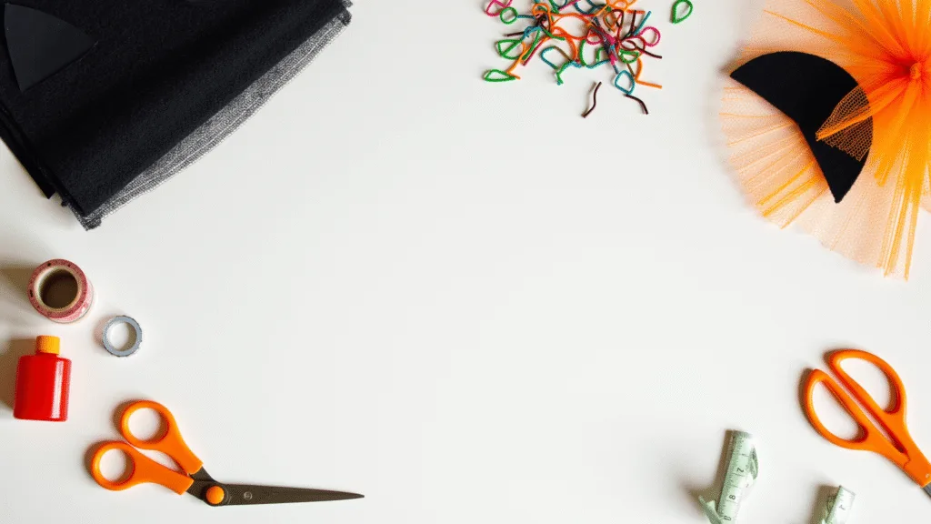 The Purr-fect Guide to Cat Halloween Costumes Bright overhead view of a minimalist craft workspace featuring Halloween cat costume materials like black fabric, felt cat ears, colorful pipe cleaners, and tulle, with neatly arranged creative tools and warm orange accents under natural lighting.